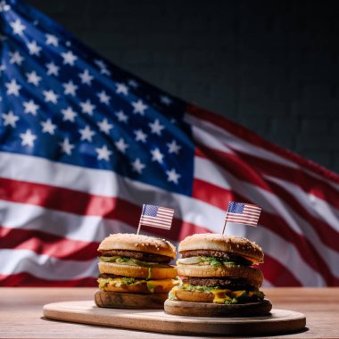 Amerika Birleşik Devletleri bayrağı sallayarak önünde ahşap kesme tahtası üzerinde lezzetli hamburger
