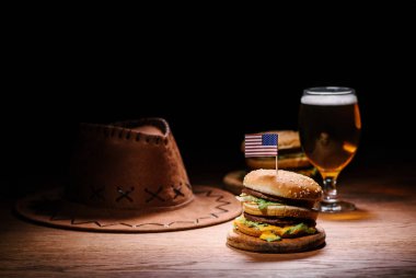 Amerikan kovboy şapkası ve bardak bira ile ahşap masa lezzetli burger