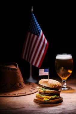 Amerikan kovboy şapkası, ABD bayrağı ve bardak bira ile ahşap masa lezzetli burger