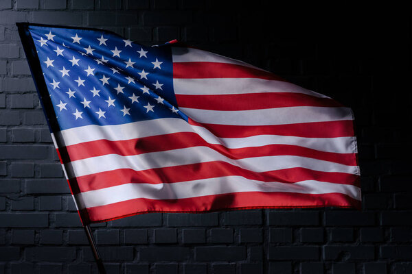 waving usa flag in front of black brick wall, Independence Day concept