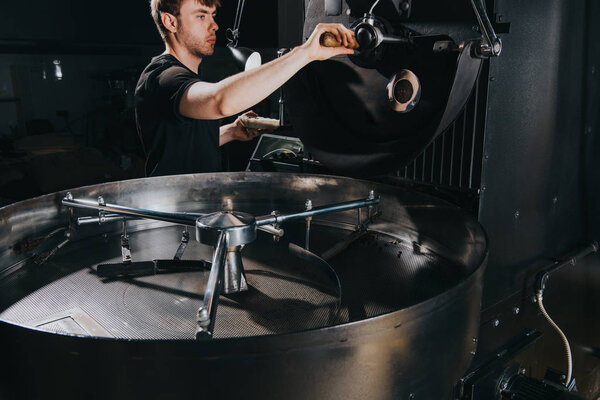 Man adjusting handle of machine for professional coffee production