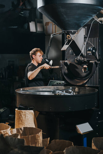 Male worker loading loading roaster with coffee beans