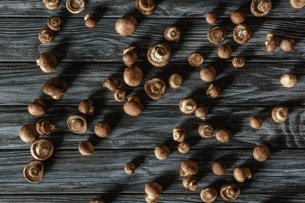 top view of spilled brown champignon mushrooms on wooden surface