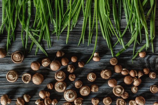 top view of champignon mushrooms with leeks on wooden tabletop