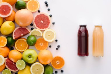 top view of citrus fruits with blueberries and bottle of fresh juice on white surface clipart