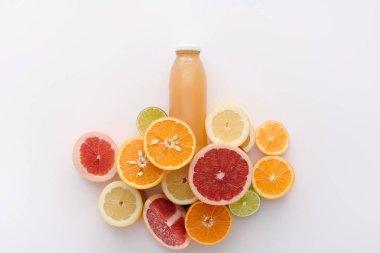 top view of bottle of juice with citrus fruits slices on white surface clipart