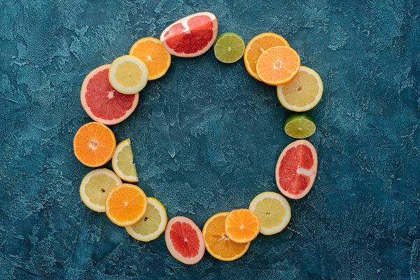 top view of round frame made of citrus fruits slices on blue concrete surface