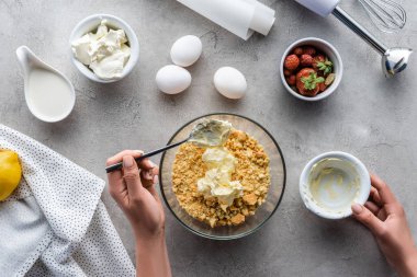 üzerinde gri masa düzenlenmiş malzemelerle ev yapımı pasta hamur yapma kadın görüntüsünü kırpılmış