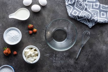 Ev yapımı pasta ve koyu gri yüzeyi boş kase için malzemelerin düzenleme ile düz lay