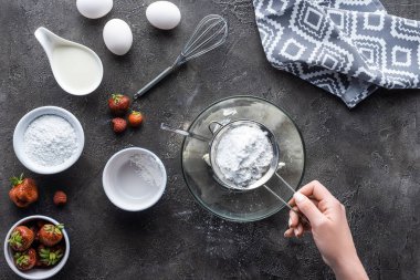 Ev yapımı pasta için krema koyu gri masa üzerinde yaparken un ekleyerek kadının kısmi görünümü