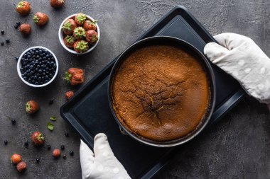 düz lay pişmiş ev yapımı pasta, koyu gri masa üzerine fırın kumaş ve taze çilek ile