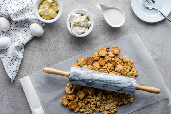 top view of arrangement of ingredients for making homemade pie and rolling pin on grey tabletop