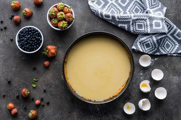 düz lay üzerinde koyu gri masa düzenlenmiş malzemelerle çiğ börek ile