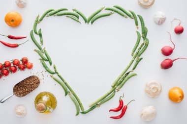 taze yeşil bezelye ve baharat üzerine beyaz izole olgun sebze ile yapılmış kalp üstten görünüm 