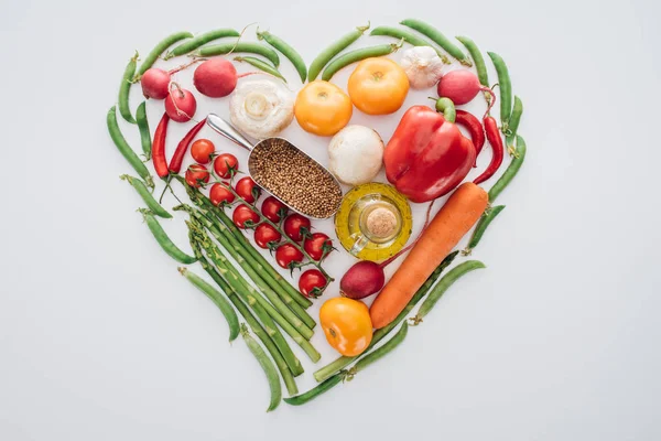 top view of heart made of green peas, asparagus and ripe vegetables with spices isolated on white 