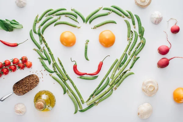 新鮮なグリーン ピース トマトと唐辛子は 白で隔離からアスパラガスとスマイリー顔の作られた心のトップ ビュー — ストック写真