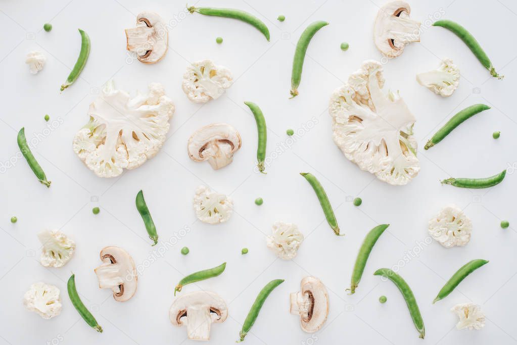 top view of fresh sliced cauliflower, mushrooms and green peas isolated on white background