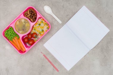 Çocuklar öğle yemeği için okul ve açık defter ile tepsi üstten görünüm mermer masada