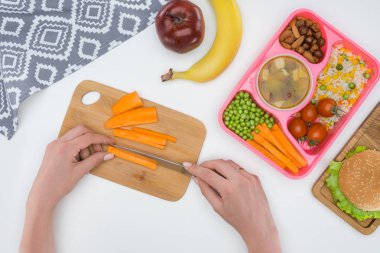 cropped image of mother preparing kids dinner for school and cutting carrot clipart