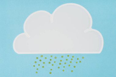 top view of white napkin in shape of cloud with rain of green peas isolated on blue clipart