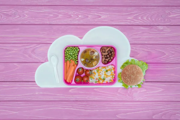 Çocuklar okul ve hamburger yemeğe tepsiye üstten görünüm pembe tablo
