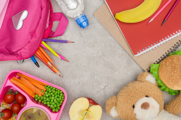 top view of tray with kids lunch for school, bag with pencils and notebooks on marble table