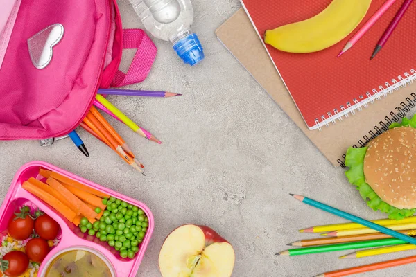 top view of tray with kids lunch for school, notebooks and pencils on marble table