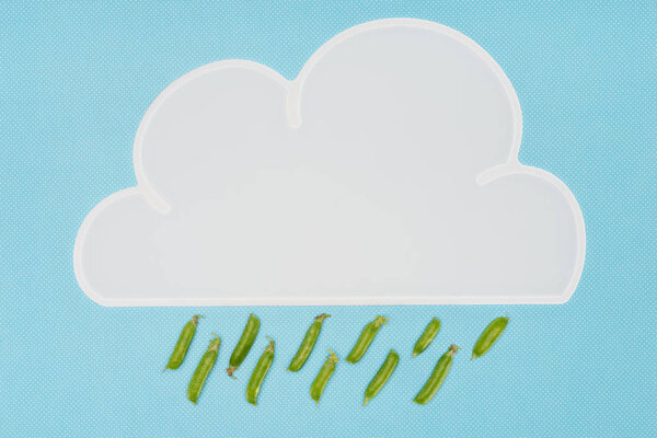 top view of white napkin in shape of cloud with rain of pea pods isolated on blue