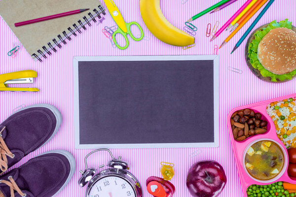 top view of blackboard and tray with kids lunch for school on violet surface