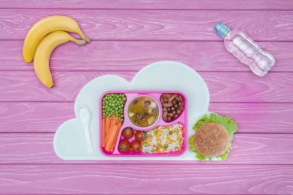 Top view of tray with kids lunch for school, bananas and bottle of water on pink table — Stock Image Top View Tray Kids Lunch School Bananas Bottle Water Pink Stock Image