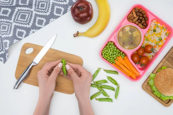 Cropped image of mother preparing kids dinner for school and holding green peas in pod — Stock Image Cropped Image Mother Preparing Kids Dinner School Holding Green Peas Stock Photo