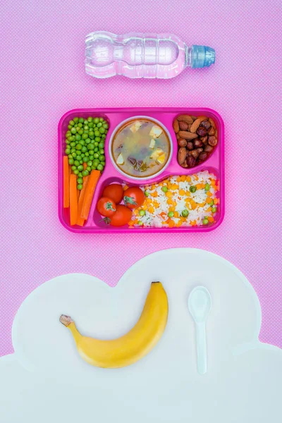 Top view of tray with kids lunch for school, bottle of water and banana on violet table — Stock Image Top View Tray Kids Lunch School Bottle Water Banana Violet Royalty Free Stock Photos