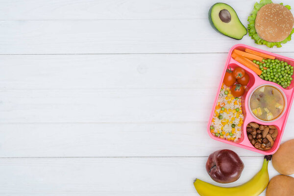 top view of tray with kids lunch for school and fruits on wooden table