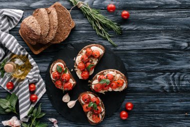 Tahıllı ekmek mozzarella ve karanlık kayrak tahta üzerinde pişmiş domates ile
