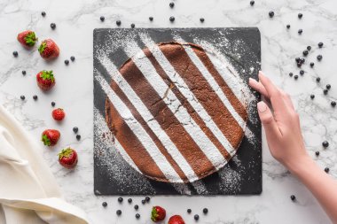 insan eli ve lezzetli ev yapımı kek frosting ile kırpılmış ve mermer yüzeyindeki taze çilek