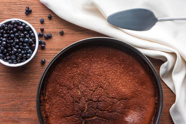 вид на вкусный домашний кекс и свежую чернику на деревянном столе
 