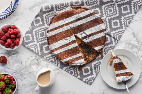 top view of tasty homemade cake on cloth and fresh berries on marble surface