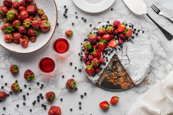 top view of delicious homemade cake, fresh berries and summer drink on marble surface 