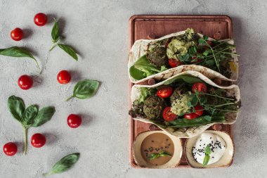 gri yüzeyi ahşap tahta üzerinde düz lay falafel ekmeği, domates ve Ayçiçeği tohumları germinated ile hizmet