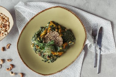 Kaju fıstığı ve ıspanak, çatal bıçak takımı ve keten panikesh üstten görünüm üzerinde gri masa üstü