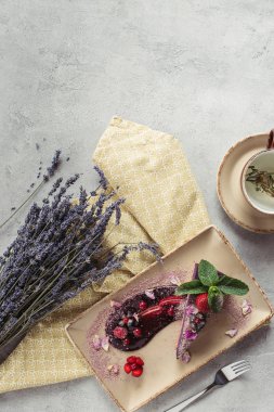Nane yaprakları ve plaka, lavanta ve bitkisel çay gri masa üzerinde mor yaprakları ile gıda kompozisyon yaban mersinli kek parçası ile servis