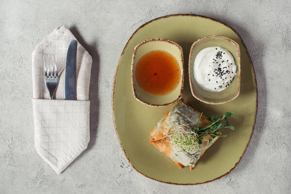 вид на самозы в филловом тесте, фаршированном шпинатом, и панир, украшенный прорастающими семенами люцерны и подсолнечника, подаваемых на тарелке на серой поверхности
