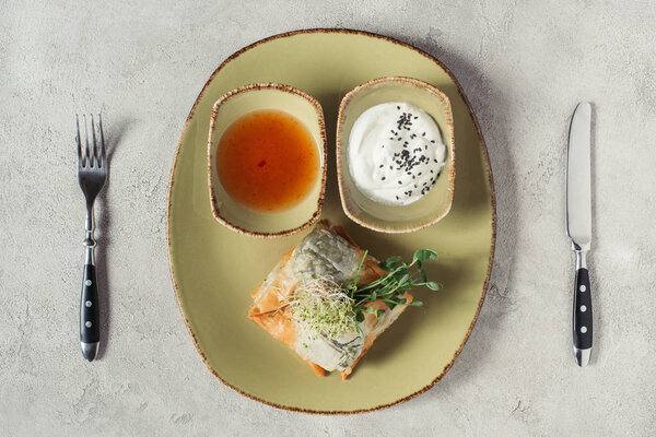 Плоский лежал с самозами в тесте филло фаршированный шпинатом и паниром украшенный прорастающими семенами люцерны и подсолнечника служил на тарелке на серой поверхности
