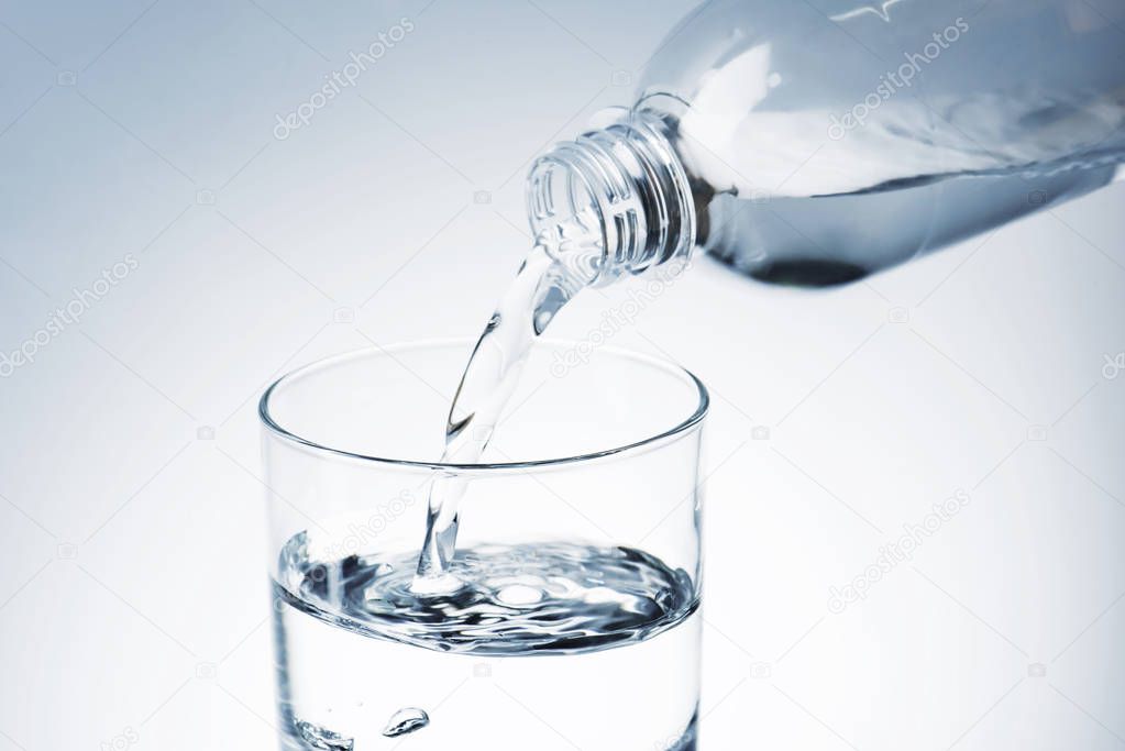 close-up shot of pouring water from plastic bottle into glass