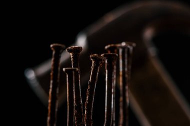  selective focus of retro rusty nails and hammer isolated on black clipart