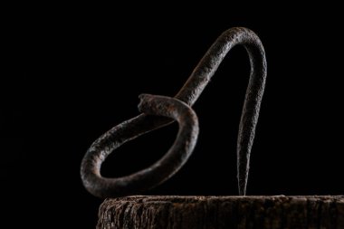  close up view of vintage hook on wooden stump isolated on black clipart