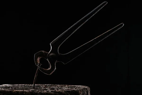 ビンテージ ペンチのクローズ アップ表示と黒に分離された木製の切り株の爪  — 無料ストックフォト