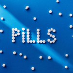 Visão elevada de pílulas de letras por comprimidos brancos em fundo azul