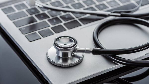 close up view of stethoscope and laptop on glass surface 