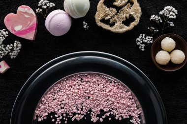top view of pink sea salt, handmade soaps and sponge on black clipart